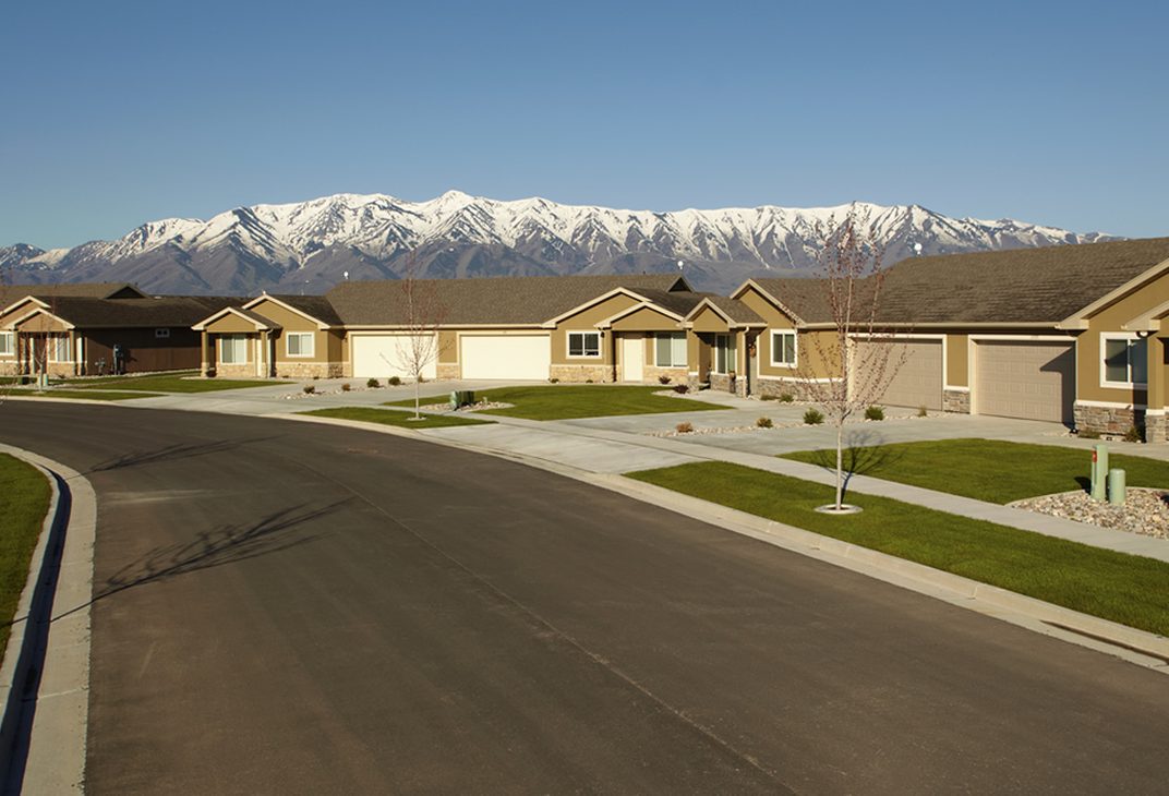 Curving street of single-level homes with snow-capped mountains