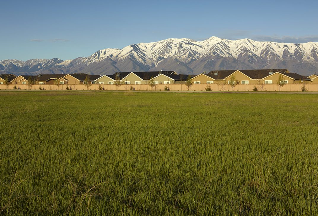 Homes beyond an open field with mountain views